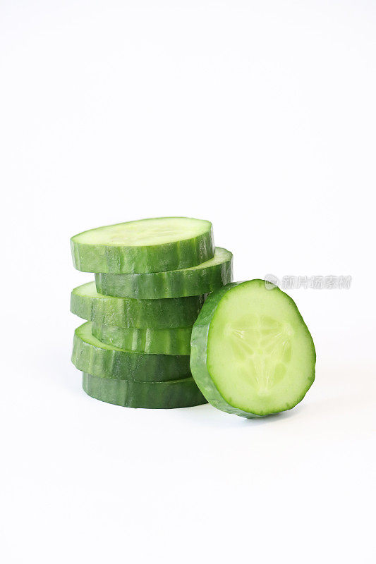 黄瓜(Cucumis sativus)切片堆叠的特写图像，显示绿色的皮，白色的肉和白色的种子，白色的背景，重点在前景